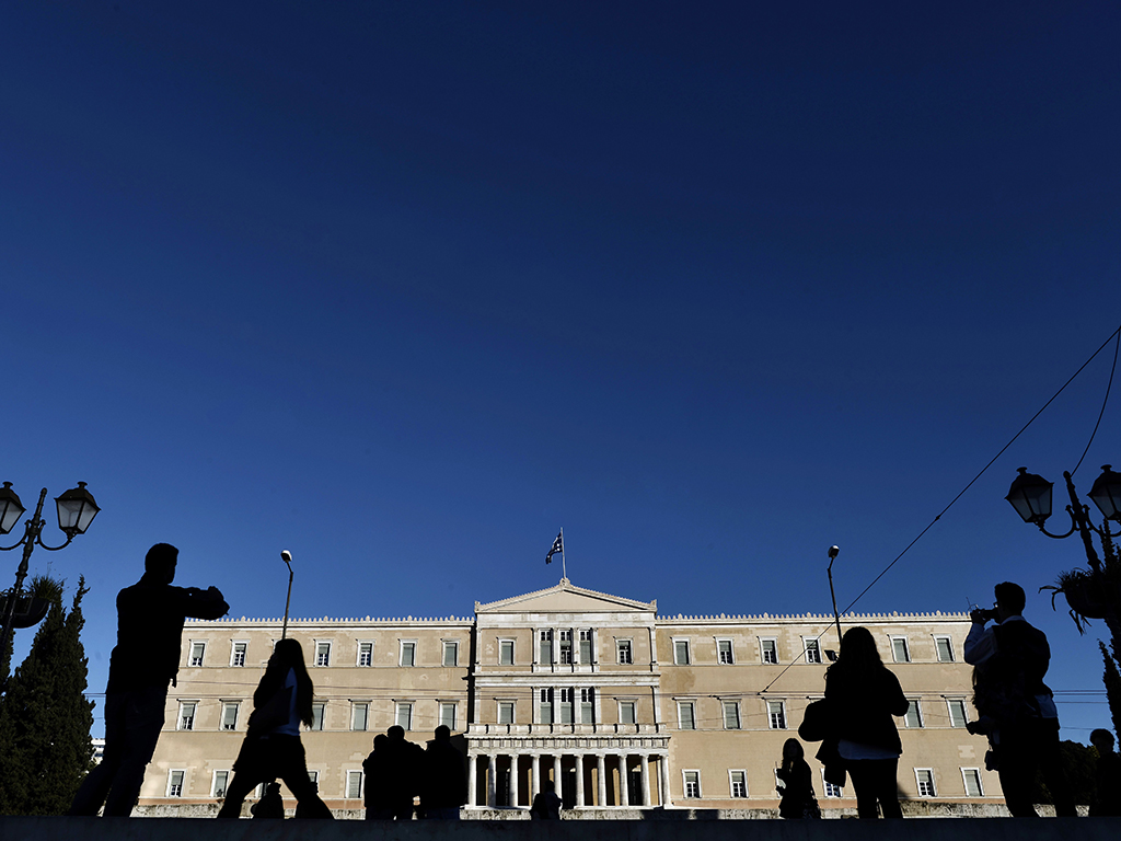 People stand by the Greek parliament in Athens. Many expect the country to be unable to obtain bailout funds by the end of this week, which is likely to throw its future into chaos